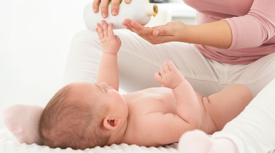 Frau gießt in Öl in Hand für Babymassage